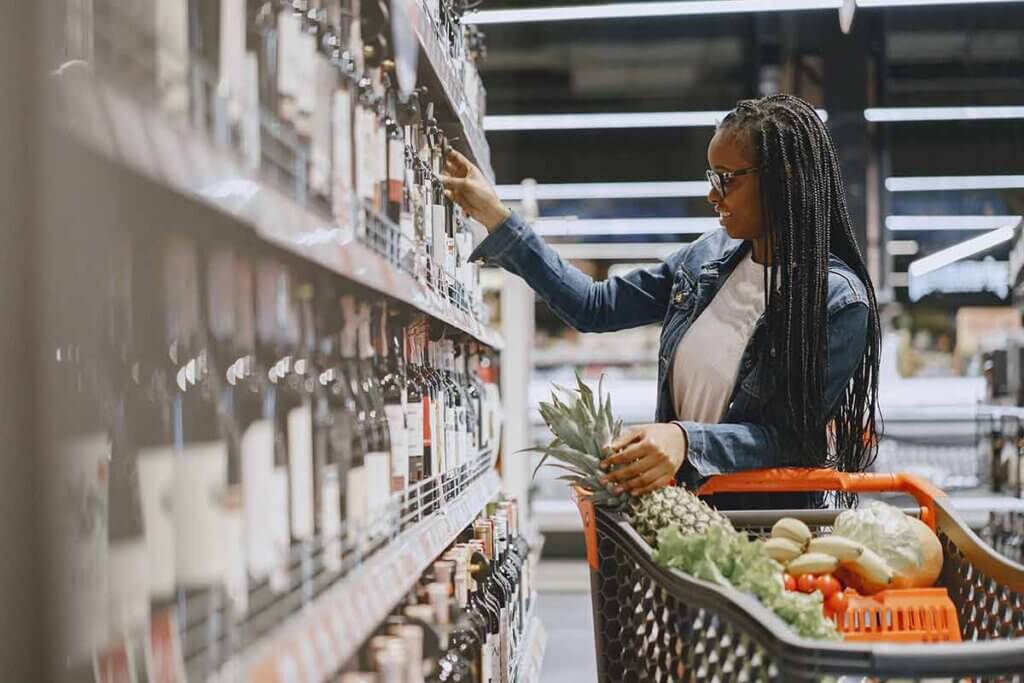 Frau schaut ein Weinregal im Supermarkt an