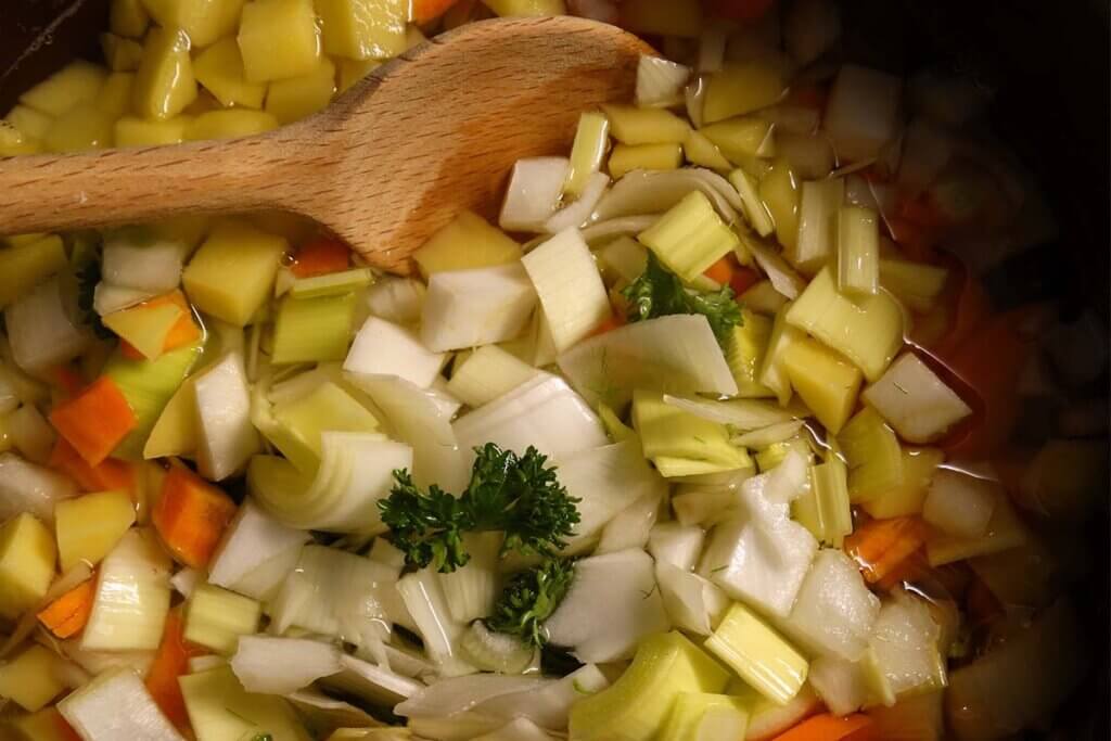 Holzloeffel in einer Suppe mit Suppengruen.