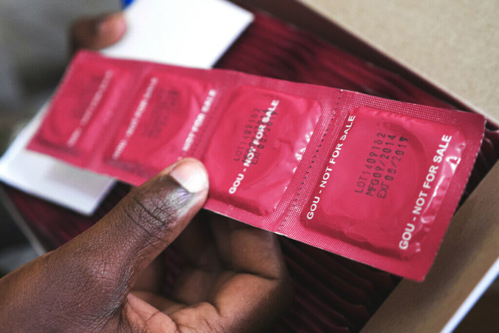 Eine Person zieht eine rote Kondomverpackung aus einer Schublade.