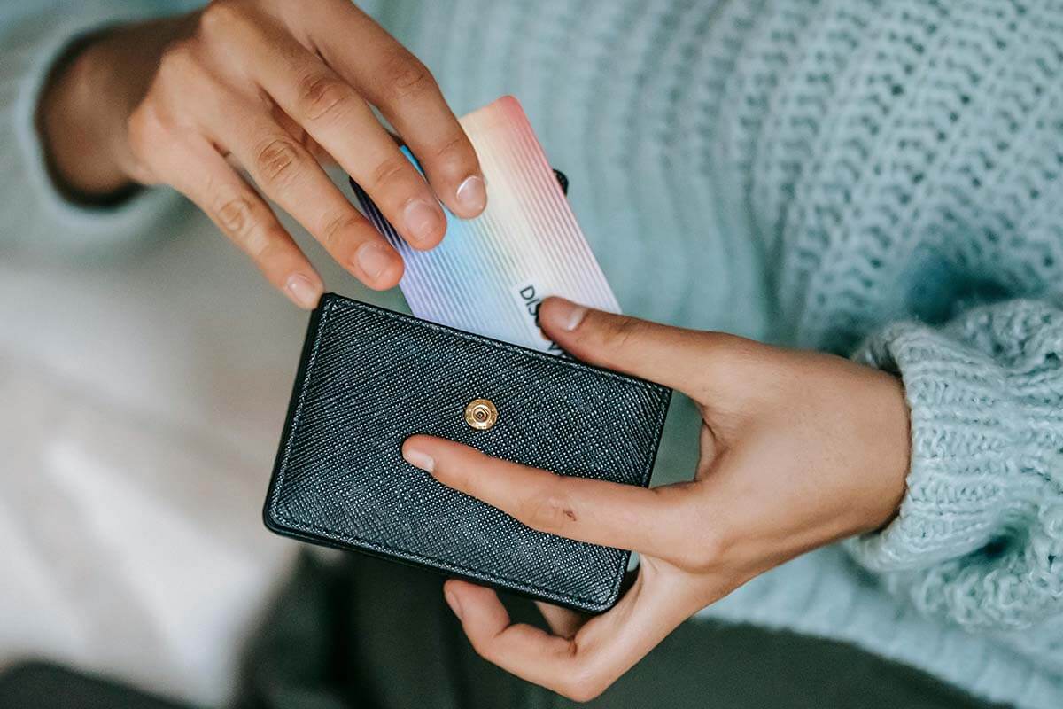 Eine Person in blauem Pulli packt eine Karte in ihr Portmonnaie.