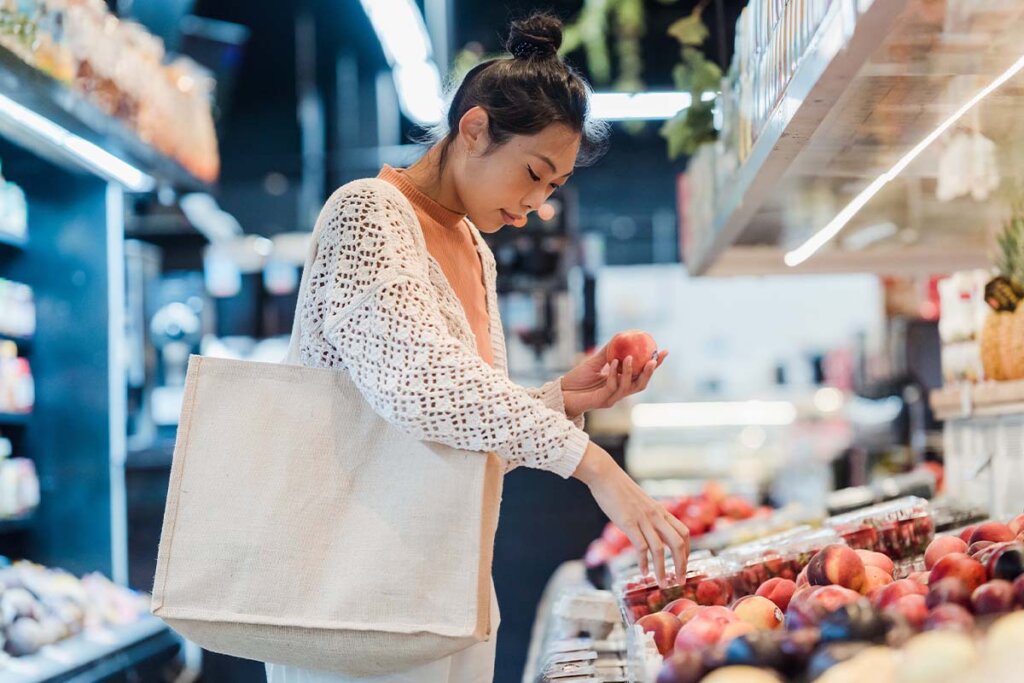 Eine Frau steht vor einem Obstregal im Supermarkt.