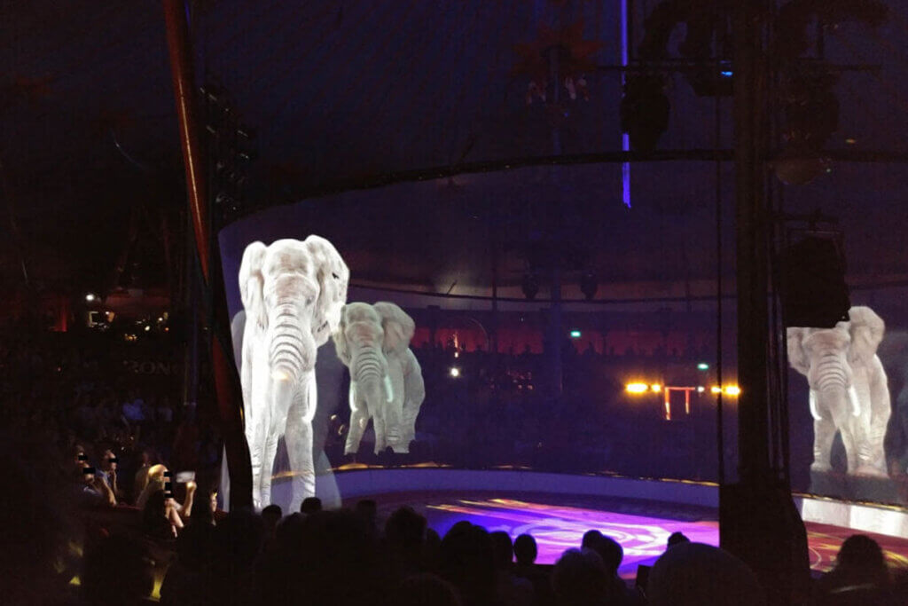 Hologrammshow von Circus Roncalli. Elefanten laufen im Kreis durch die Manege.