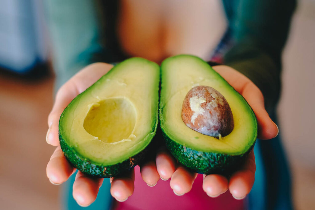 Frau haelt Avocado in den Haenden