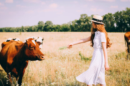 Eine Frau mit Kuh auf einer Weide.