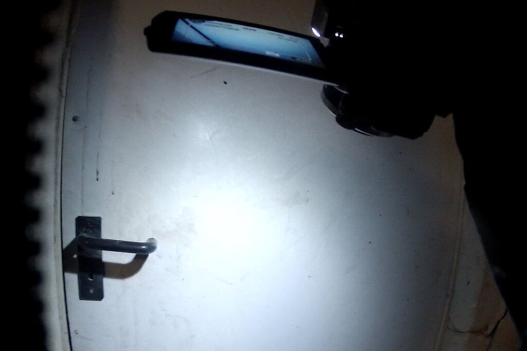 Person leuchtet mit einer Taschenlampe an eine Tuer