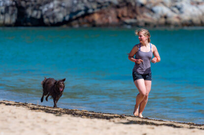 frau rennt mit dem hund am strand