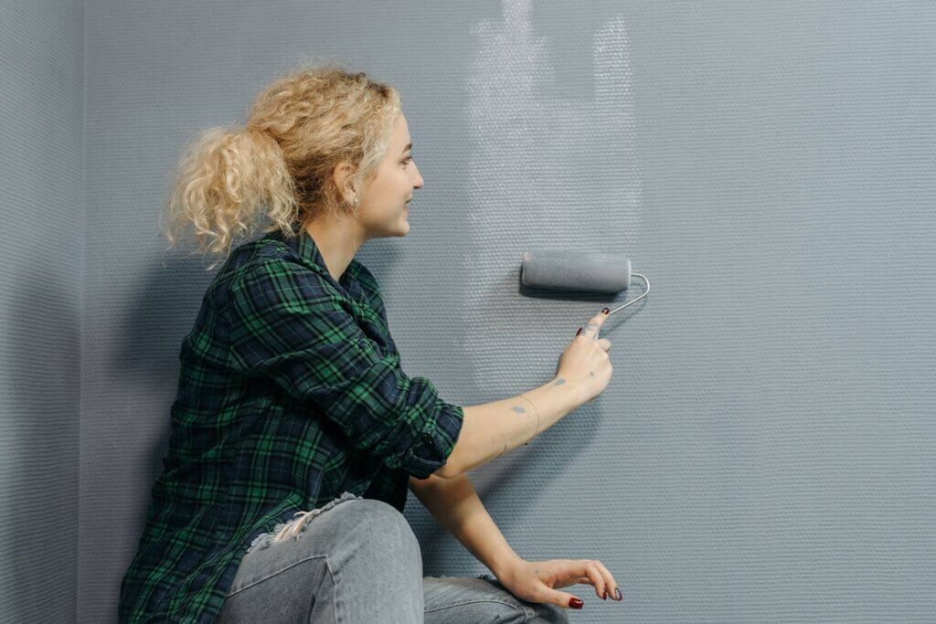 Frau streicht Wand mit Malerrolle