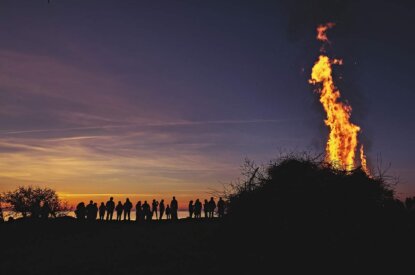 Menschen stehen vor einem Osterfeuer