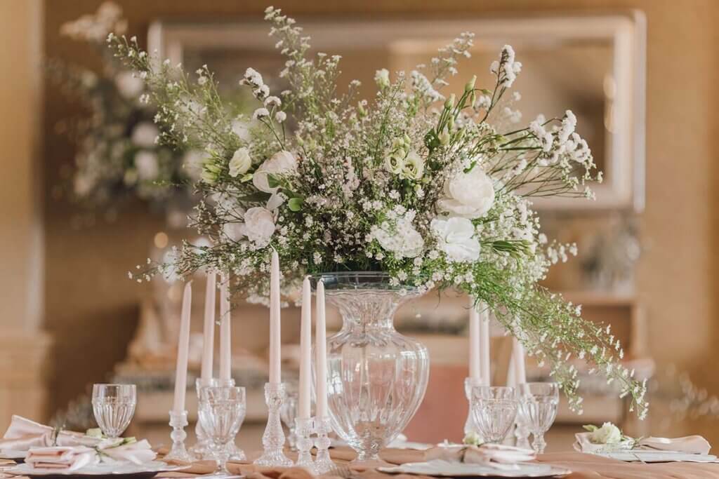 Ein gedeckter Hochzeitstisch mit Blumen.