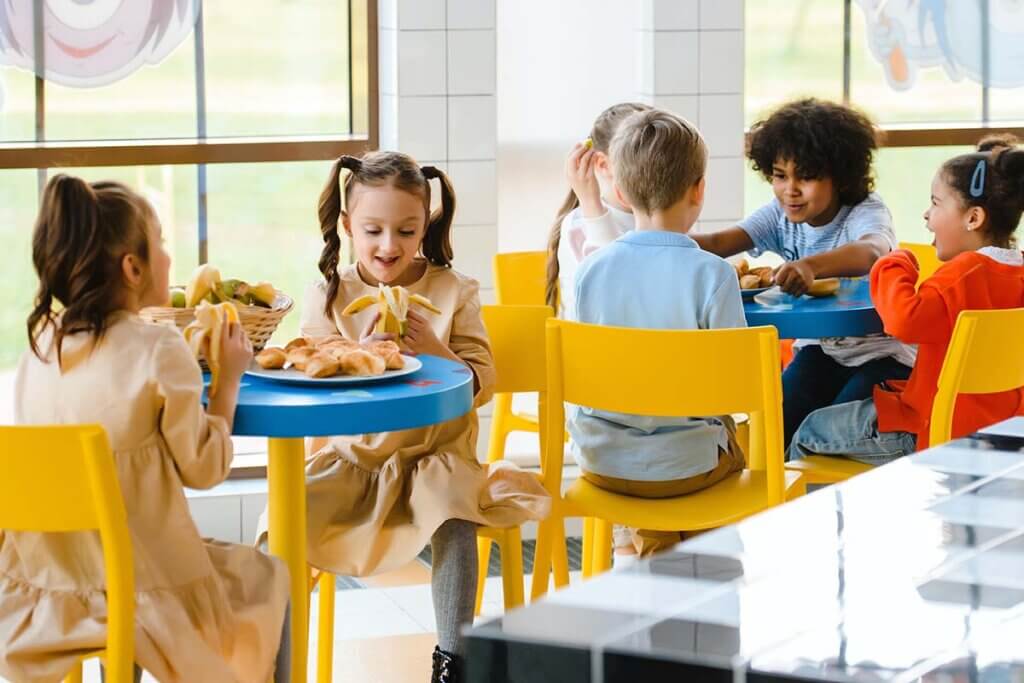Kinder essen an Tischen