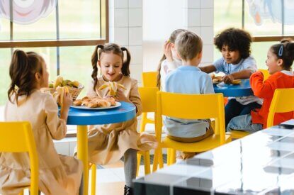 Kinder essen an Tischen