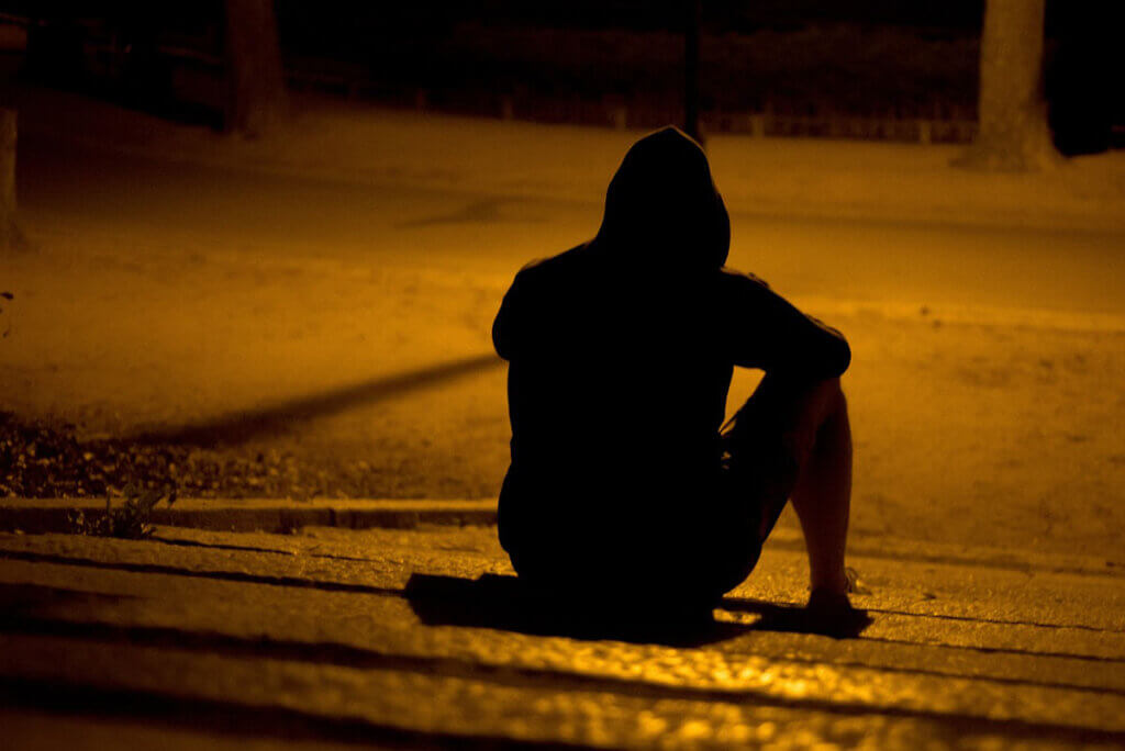 mann sitzt im dunkeln auf der strasse