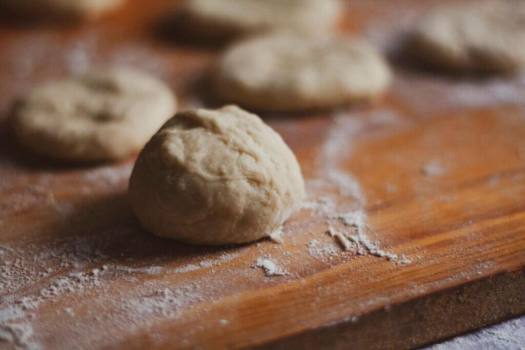 Teigbällchen mit Mehl auf einem Holzbrett