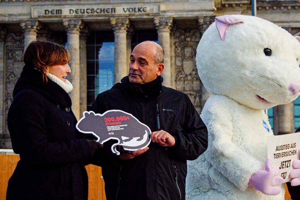 Uebergabe eines Schildes in Form einer Ratte mit dem Titel 200000 Unterschriften fuer Ausstieg aus Tierversuchen.