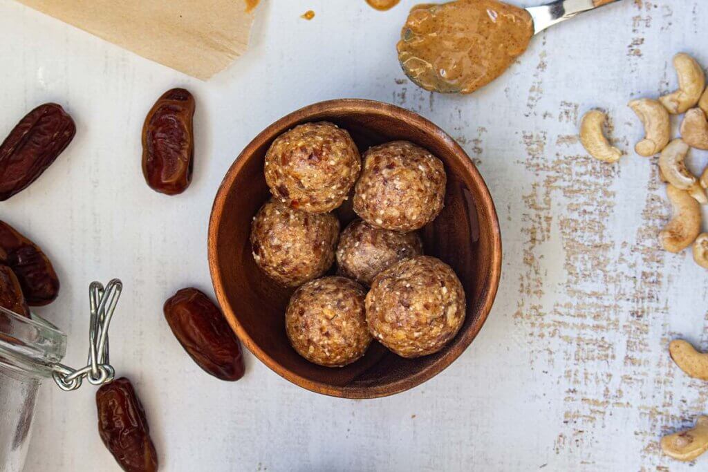Vegane Energy Balls liegen in einer Holzschuessel.