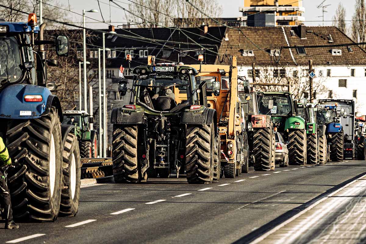 Ein Bauernprotest, Traktoren fahren in einer Reihe auf der Strasse.