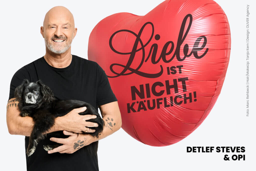 Detlef Steves mit Hund Opi auf dem Arm vor einem Ballon mit Aufschrift "Liebe ist nicht käuflich"