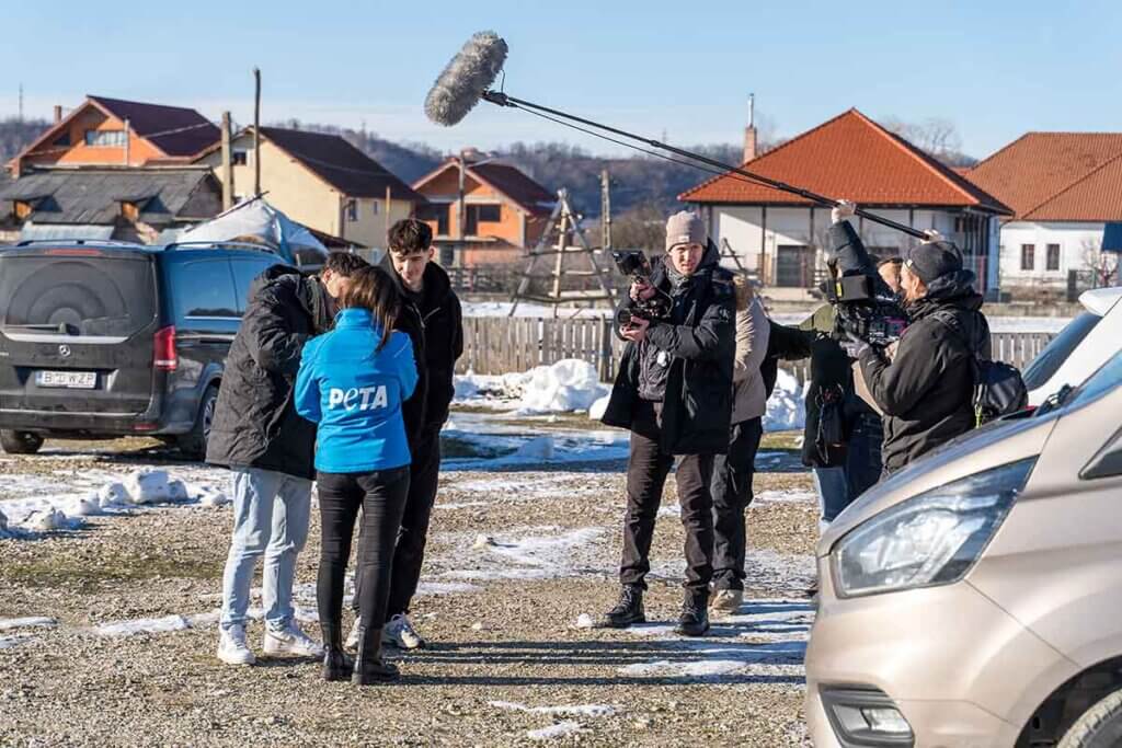 Jana Hoger im einem Dorf mit Restschnee auf den Wiesen, einem Drehteam von Pro7 und 2 anderen Helfern.