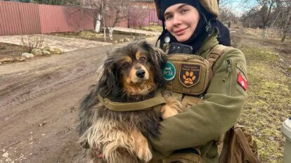 Sabrina hält einen geretteten Hund in den Armen und schaut freudenstrahlend in die Kamera.