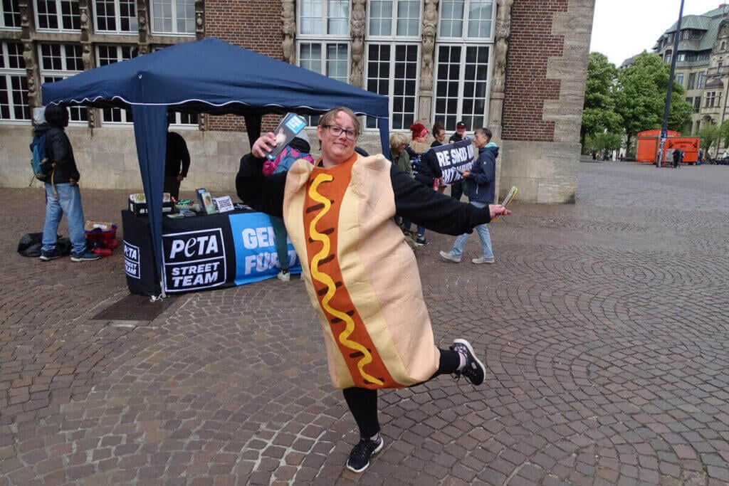 PETA Stand auf einem Platz. Person im Hot Dog-Kostüm.