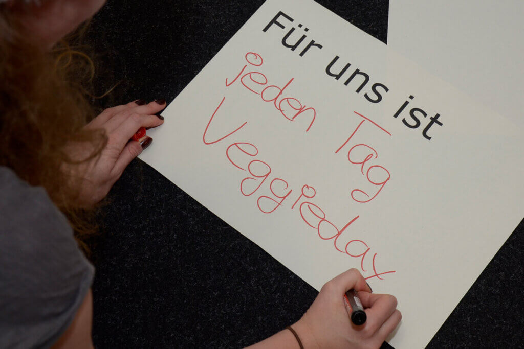Person schreibt auf Schild "Für uns ist jeden Tag Veggieday"
