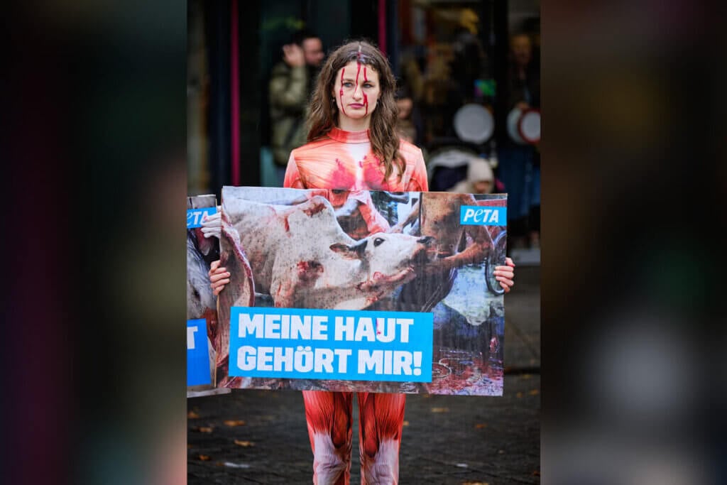 Person in Muskel-Morphsuit mit Demonstrationsschild