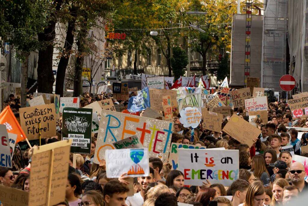 Eine Demonstration mit vielen Menschen und laufen einer Allee entlang.