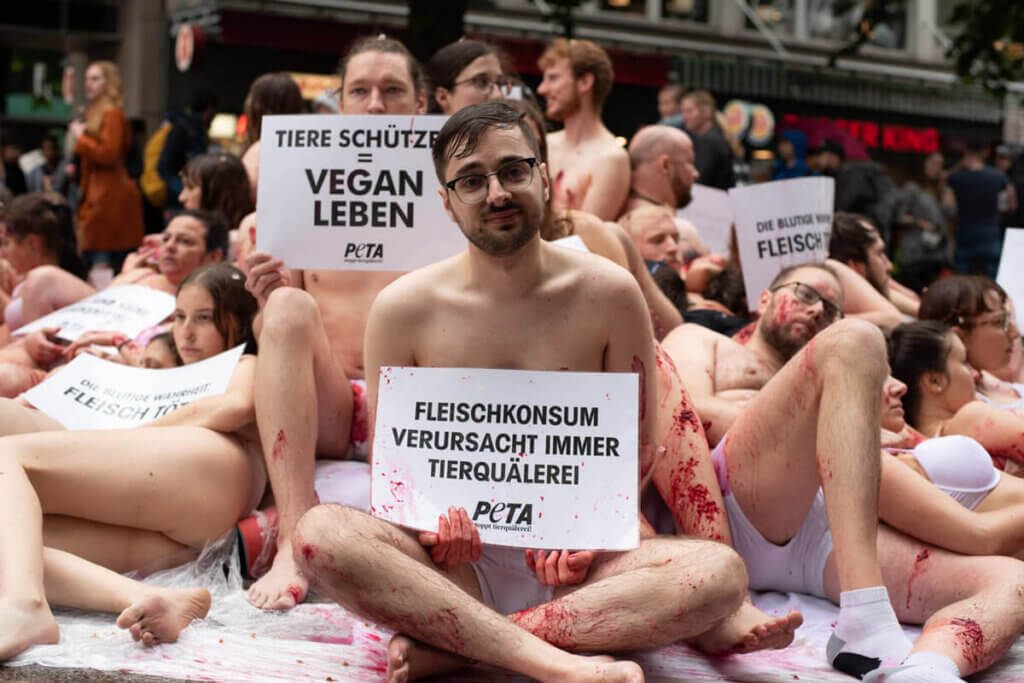 Leicht bekleidete Menschen auf einem Haufen zur Demonstration gegen Fleischkonsum
